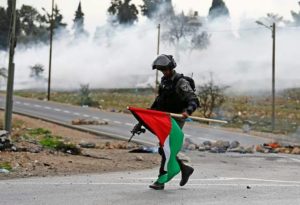 חייל ישראלי מחזיק את דגל פלסטין