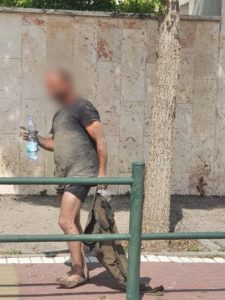 בצילום: תושב קריית חיים לאחר שחולץ עם בקבוק שתיה שהעניקו לו עובדי העירייה